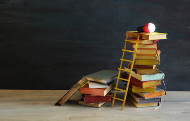 stack of books, a light bulb and the ladder of success,ideas,innovation, business,reading,...