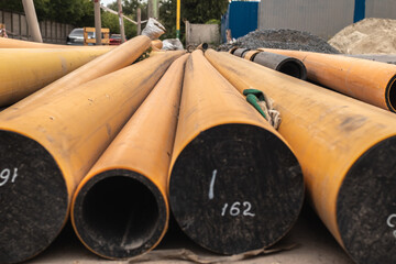 A pile of pipes lies on the edge of the roadway.