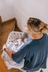 Young woman drying laundry on balcony during slow morning at home. Real moment, Gen Z lifestyle,...