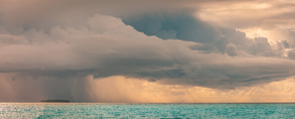  Dramatic tropical seascape showing storm clouds and heavy rain over the ocean horizon, moody...