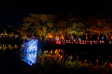 A serene alley illuminated by rows of glowing lanterns suspended above, casting warm light onto the...