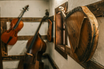Rustic cottage interior with bandura foreground, double bass and violin hanging on white-washed...