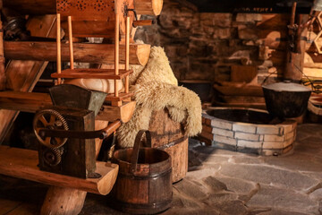 Rustic cottage workshop scene with antique hand-crank grain mill, wooden cheese press, sheepskin-covered barrel, bucket and stone hearth, celebrating traditional rural craftsmanship