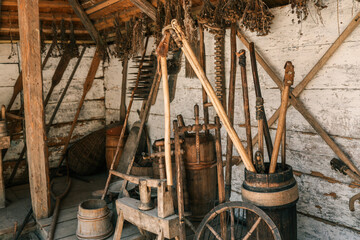 Vertical view of traditional barn interior with assorted antique wooden farm tools, hanging dried...