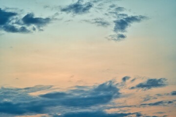 Obraz premium Western sky at sunset. A relaxing scene of day's end with gentle clouds stretching across the horizon. Shades of blue and orange