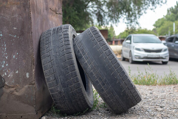 Two worn out tires with bald treads next to a trash can