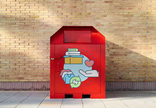 Bright red donation bin for used clothing stands against a brick wall, inviting contributions at any time to support those in need. PSD template mockup.