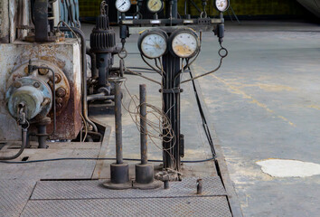 Vintage industrial equipment with pressure gauges, valves, and wires in an old factory hall....