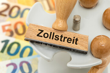 Ein Holzstempel ist beschriftet mit dem Aufdruck Zollstreit, zwischen USA, Europa und Deutschland
