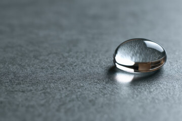 macro shot of single water droplet resting on matte metallic surface illuminated by soft light