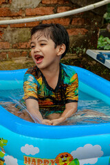 Boy Laughing While Playing in a Blue Inflatable Pool