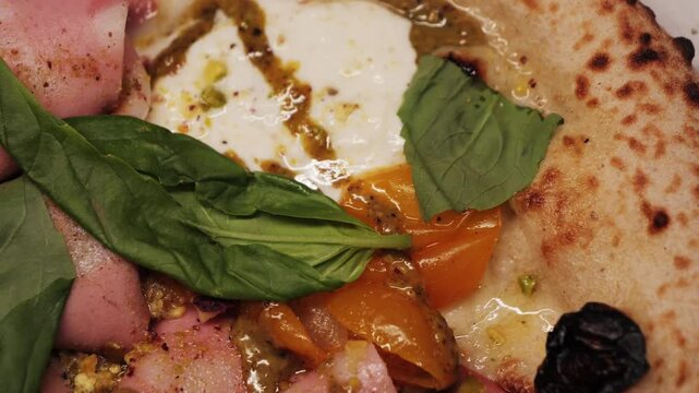 Delicious pizza with cheese mozzarella, sausage mortadella with pistachio, stracciatella burrata and tomatoes cherry yellow. Concept of italian food and cuisine. High quality 4k footage