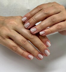 Hands with nude glitter manicure on natural nails close up. Female hands with short natural nails...