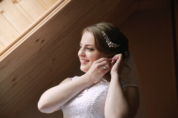 A bride is getting ready for her wedding and is putting on her wedding veil