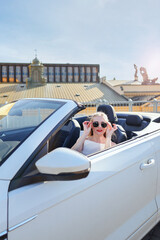 Urban summer vibe, woman in car roof down, sunglasses on, ready to go