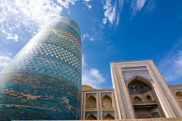 Low angle view of Kalta Minor Minaret and madrasa portal in Khiva, Uzbekistan. Iconic turquoise tower and Islamic architecture under clear sky.
