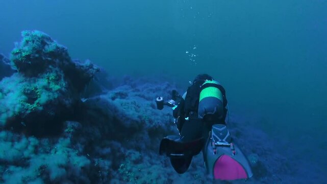 A scuba diver explores the depths of the Atlantic ocean, around the volcanic rock formations of the coast of La Palma, Canary Islands, during a clear summer day.