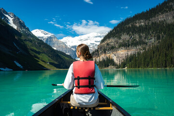 Woman paddling a canoe on turquoise lake