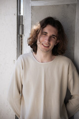 Young man smiling while standing by the doorway in a sunlit space during a warm afternoon