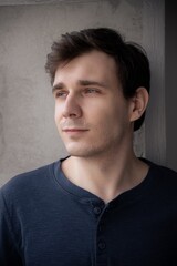 Obraz premium Man gazing thoughtfully by a window in soft indoor lighting, moments captured in contemplative silence during a quiet afternoon