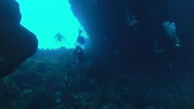 Scuba divers explore underwater caves illuminated by early morning sunlight in La Palma, Canary Islands. The aquatic world reveals its unique geological formations and diverse marine life.
