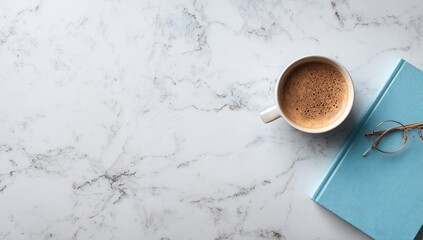 Overhead view of a coffee cup, book, and glasses on a marble surface