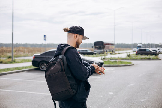 Young man in casual urban style checking smartwatch outdoors.