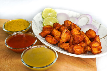 Close up image of chicken or fish pakora with tomato ketchup, chilli sauce and kasundi or mustard...