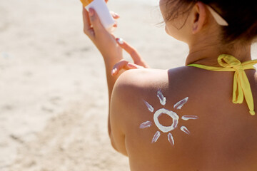 Sunscreen on tanned shoulder. Sun protection. Beautiful woman in bikini applying solar cream.  Skin...