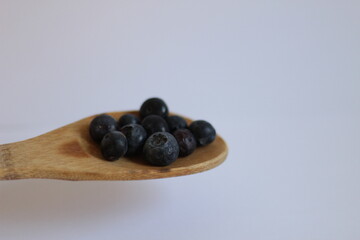 Arándanos en cuchara de madera (fondo blanco)