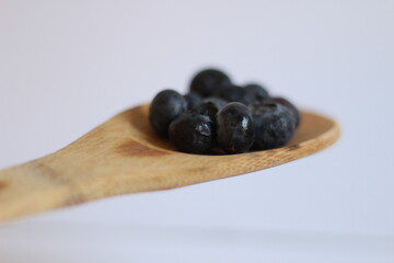 Arándanos en cuchara de madera (fondo blanco)