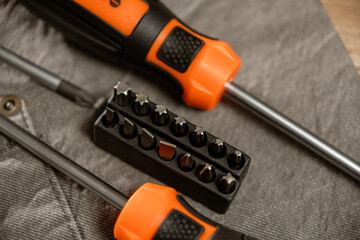Screwdrivers and precision bits arranged on a textured surface showcasing craftsmanship tools in a...