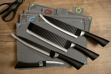 Modern kitchen tools arranged neatly on a wooden table with colorful cutting mats for food...