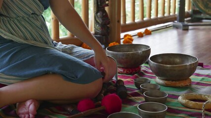 The girl's hands play on singing bowls sitting on the floor. Singing bowl playing ceremonies