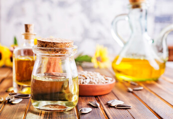 Closeup photo of sunflower oil with seeds on wooden background.