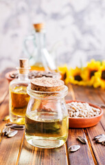Closeup photo of sunflower oil with seeds on wooden background.