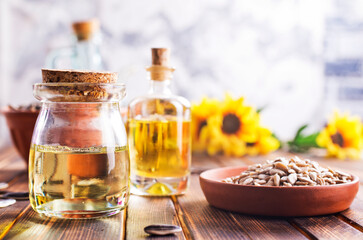 Closeup photo of sunflower oil with seeds on wooden background.