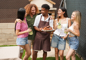 Cheerful friends enjoying a barbecue, holding grilled food and drinks, having fun together in the backyard