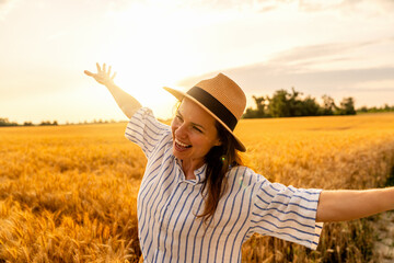 Happy woman walking with airplane arms through cereal field in rural landscape