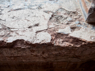 Close up view of a weathered, cracked stone wall displaying layers of deterioration and the passage...