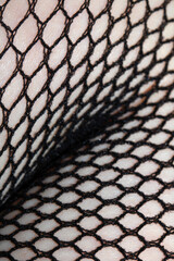 Close up of black fishnet tights on skin legs curves abstract background
