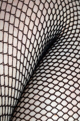 Close up of black fishnet tights on skin legs curves abstract background