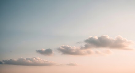 Obraz premium Pastel clouds drift across a gradient sky transitioning from pale blue to soft peach