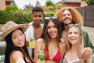 Group of cheerful multi-ethnic friends enjoying summer party, drinking cocktails and taking selfie