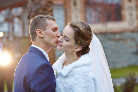 A bride and groom kiss each other on the cheek