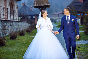 A bride and groom are walking down a path in a garden