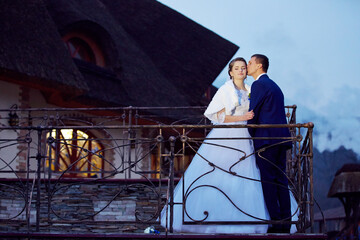 A bride and groom are kissing on a balcony