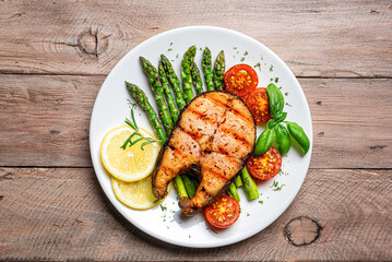 Grilled salmon steak with green asparagus, tomatoes and lemon slices