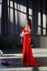 gorgeous girl in red dress with bouquet of red roses
