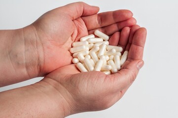 A close-up shows cupped hands holding a pile of white pills, emphasizing healthcare and medication.